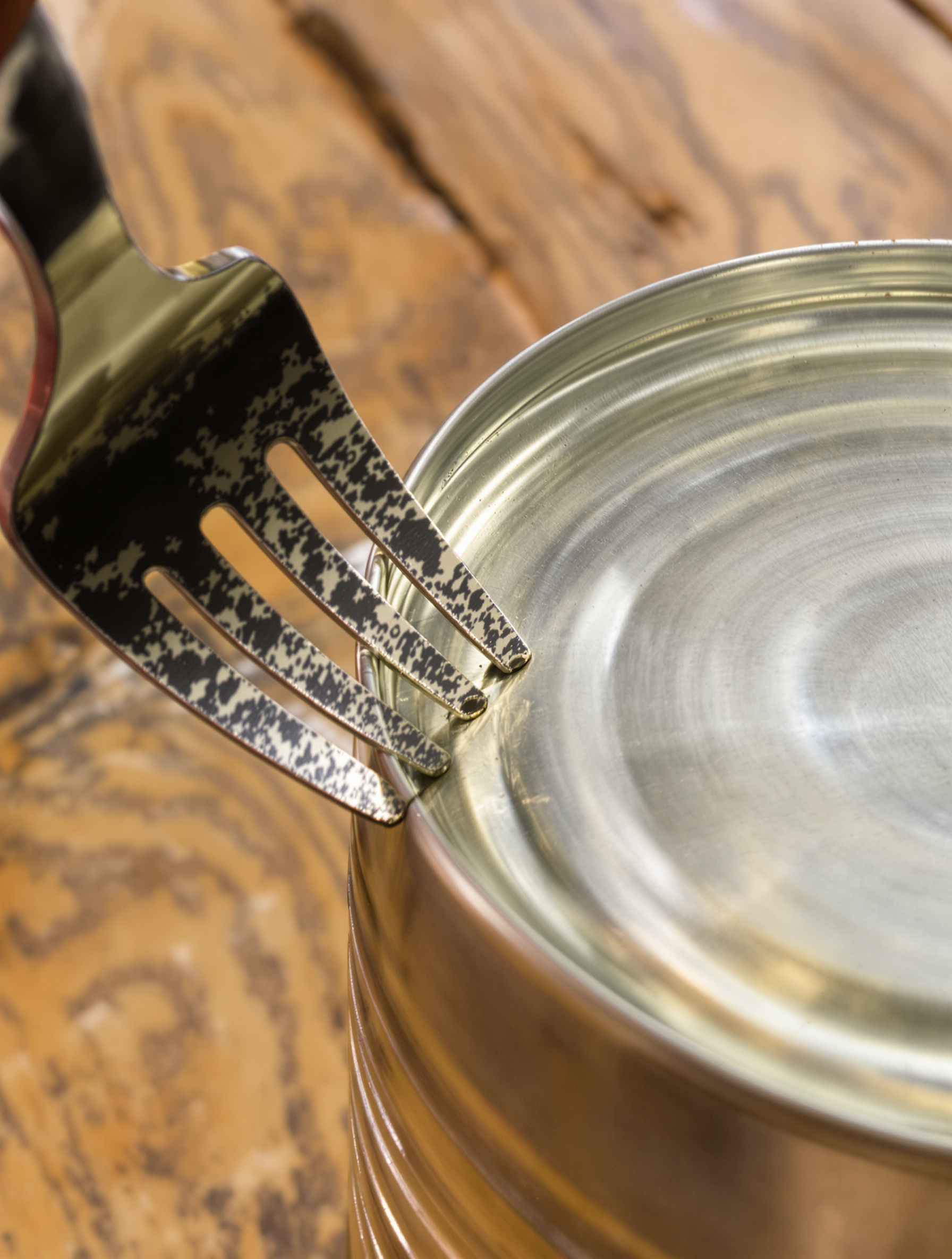 Une fourchette solide dont une dent est utilisée pour percer méthodiquement une série de petits trous rapprochés le long du serti d'une boîte de conserve.