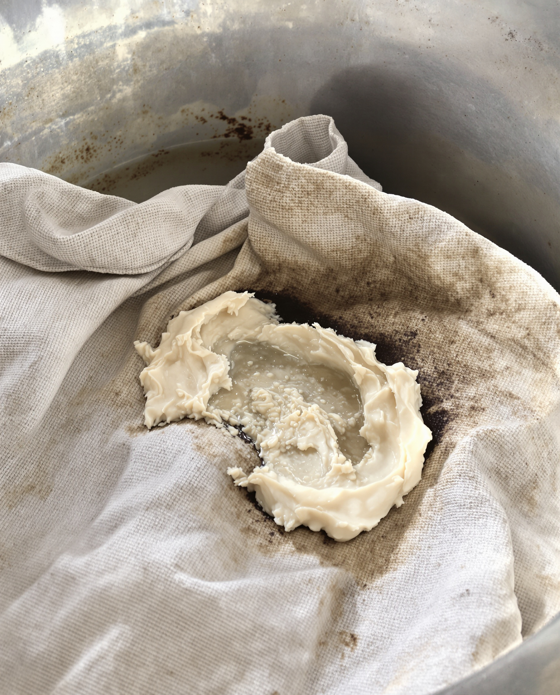 Vêtement en coton brut trempant dans une bassine en zinc avec pâte de savon de Marseille appliquée localement.