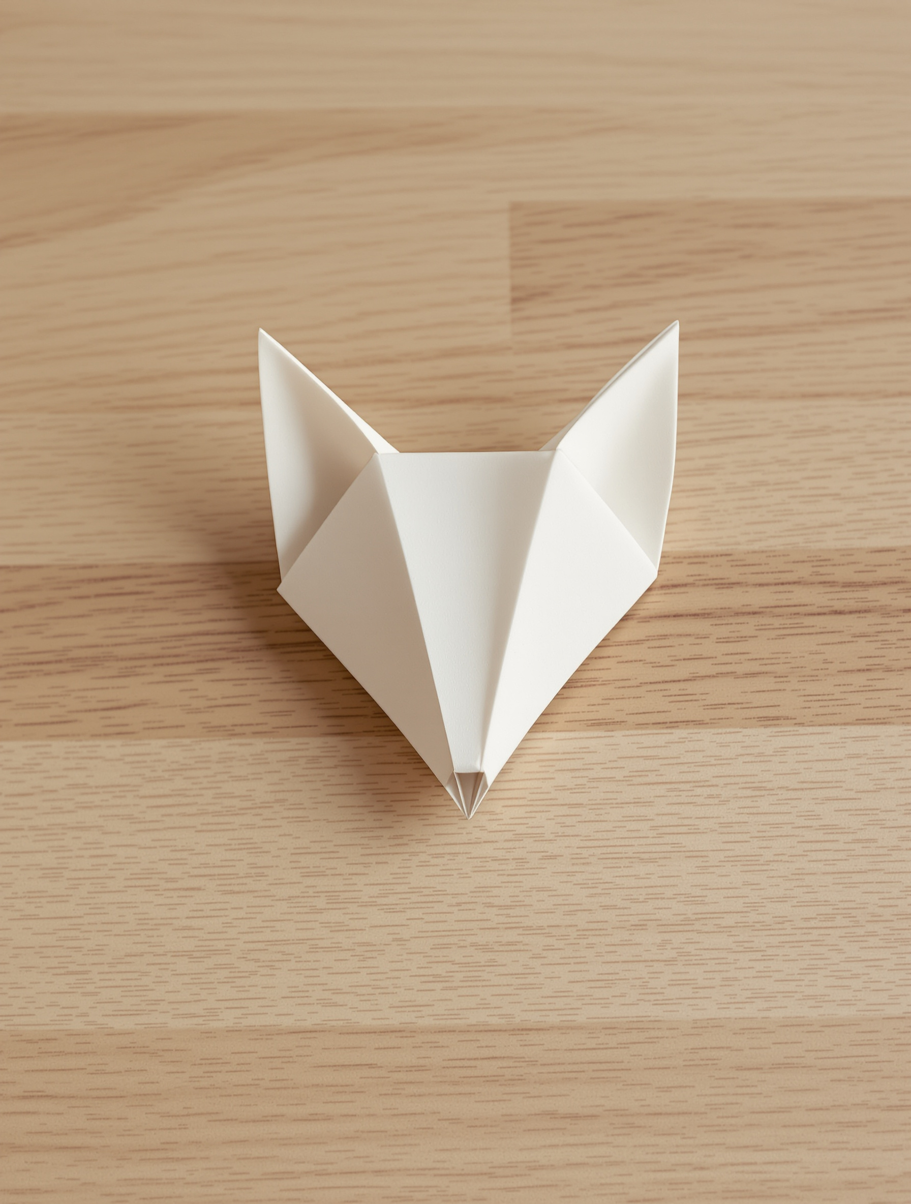 Tête de renard en origami sobrement posée sur une surface bois brut